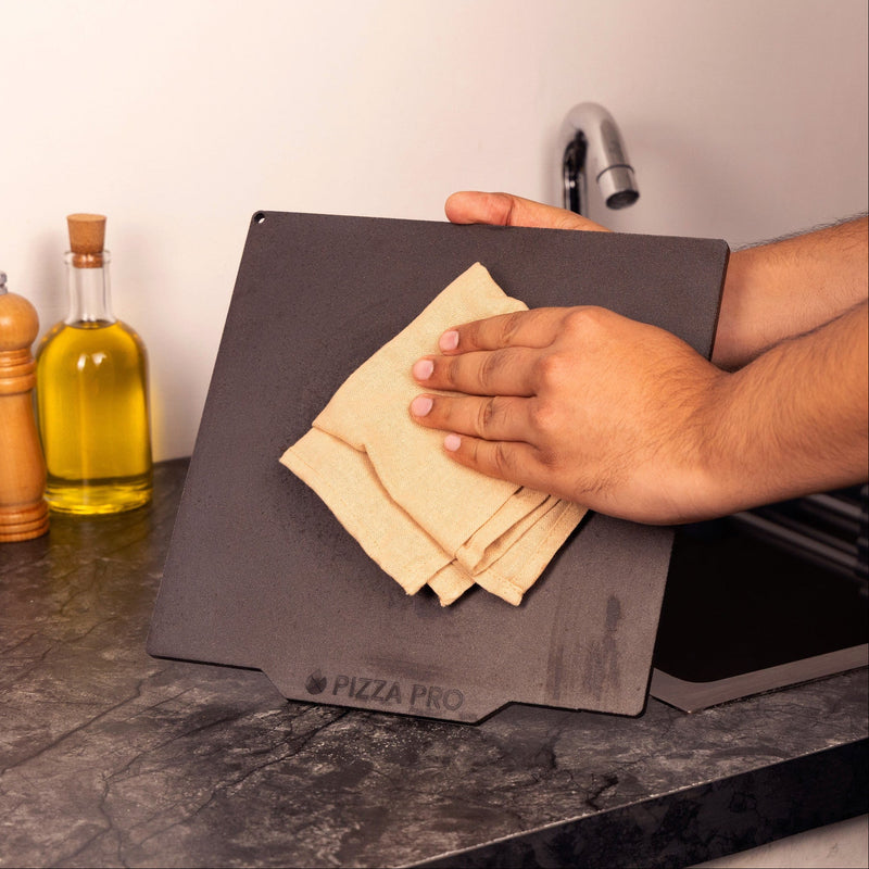 Wiping a Pizza Pro Baking Steel dry with a cloth.