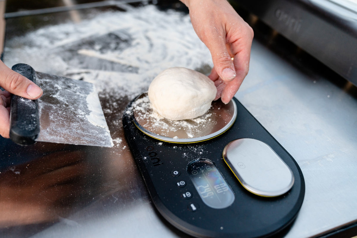 Weighing a ball of pizza dough on digital kitchen scales.